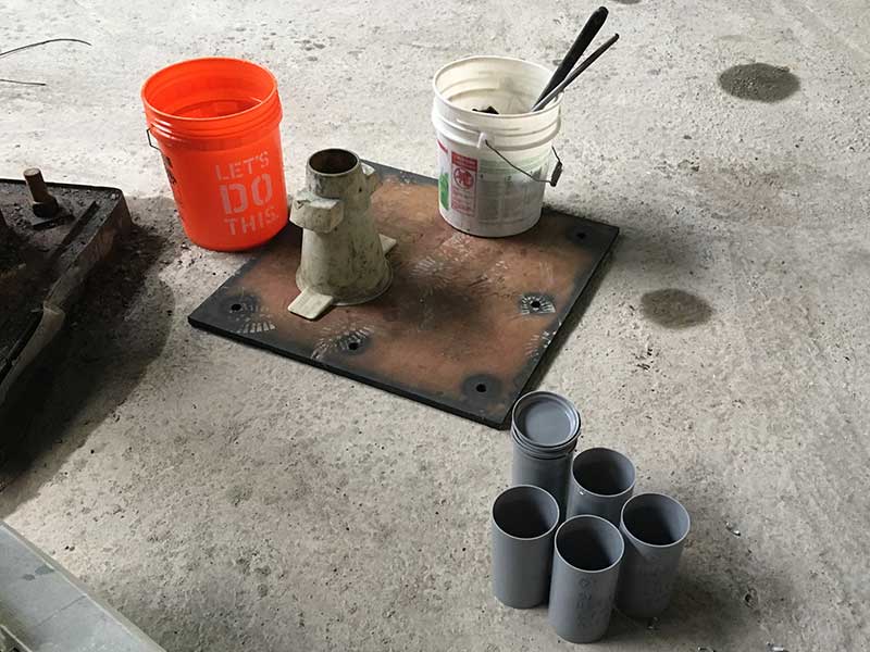 Photo of concrete testing tools in the field: slump cone and empty cylinders