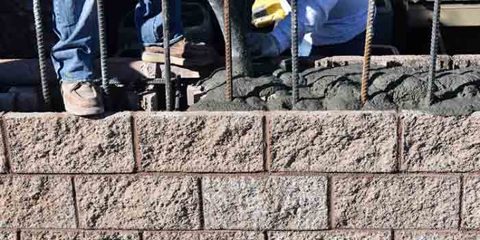 Photo of masons installing grout in CMU voids